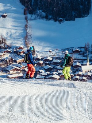 Zwei Skifahrer schauen von der Skipiste aus runter ins Dorf Alpbach | © Ski Juwel Alpbachtal Wildschönau | shootandstyle 