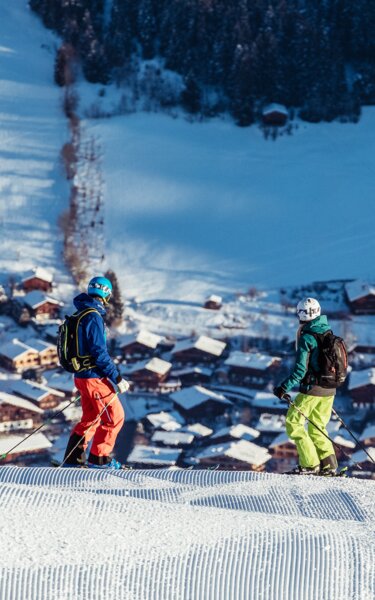 Zwei Skifahrer schauen von der Skipiste aus runter ins Dorf Alpbach | © Alpbachtal Tourismus| shootandstyle 