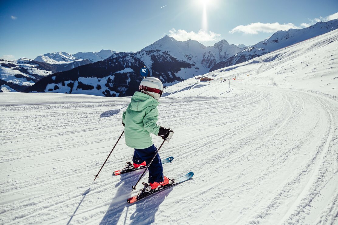 Ein kleines Mädchen im türkisfarbenem Skianzug fährt der Piste entlang  | © Alpbachtal Tourismus | shootandstyle 