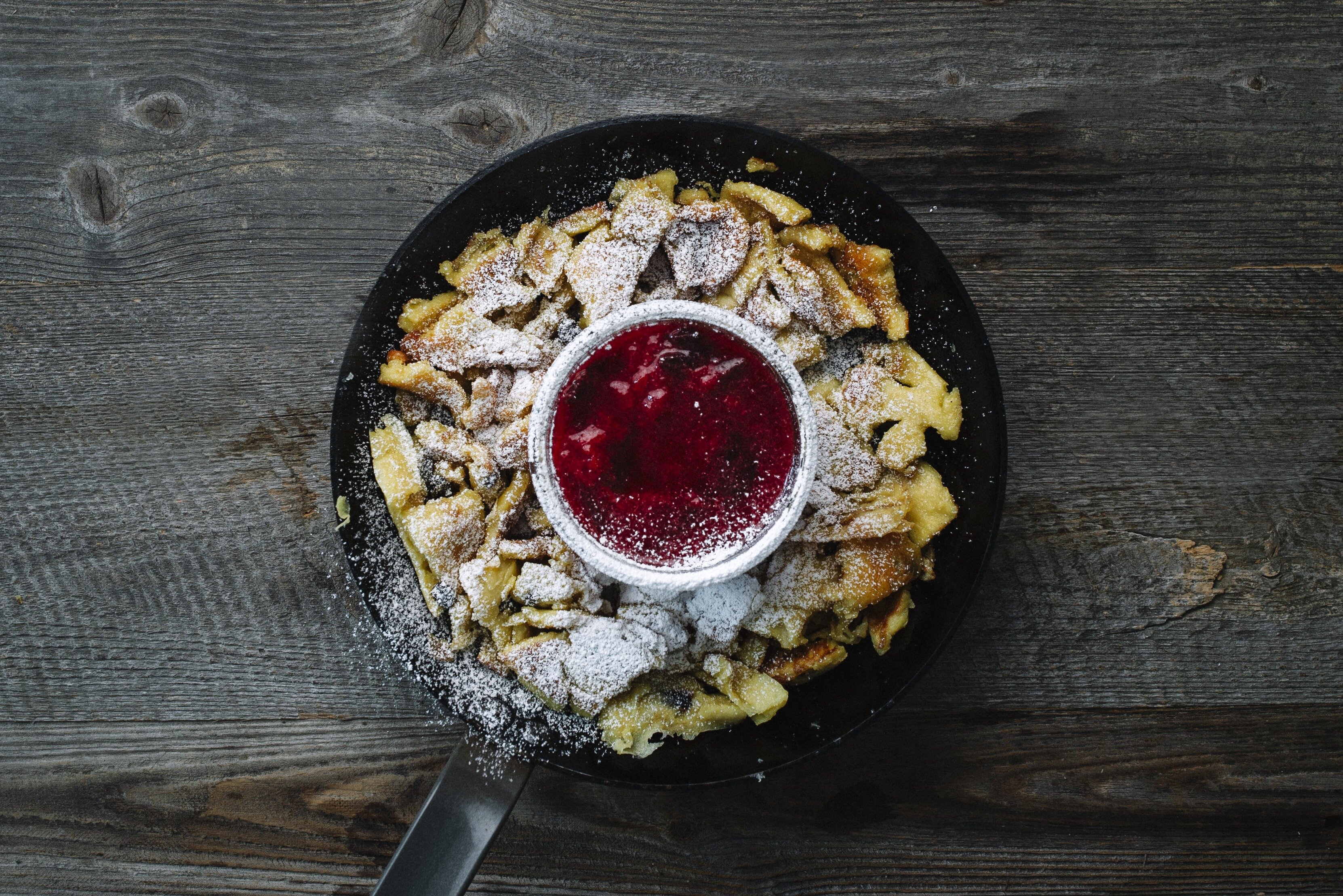 Auf dem Bild zu sehen ist eine Pfanne voller Kaiserschmarrn und in der Mitte eine kleine Schüssel voller Preiselbeeren | © Tirol Werbung | Kathrin Konschitzki 