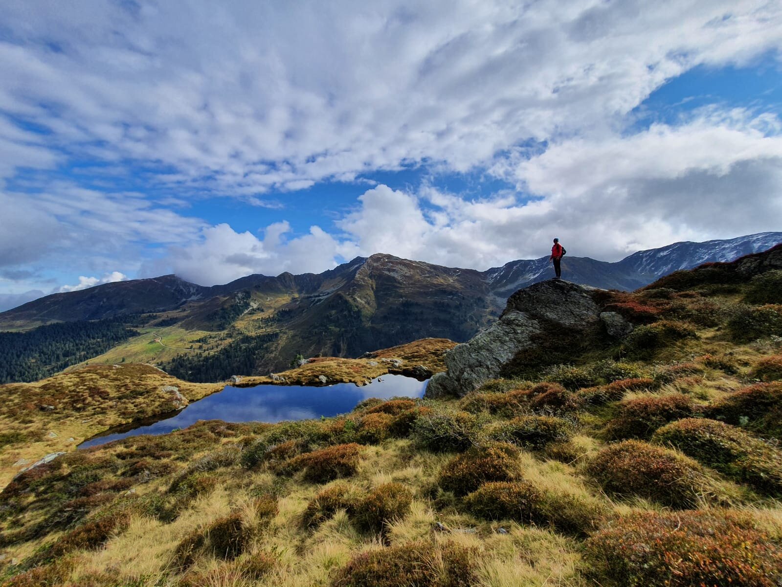 Auf diesem Bild  zu sehen ist eine Frau auf einem großen Felsen, sie genießt die Aussicht auf die Berge und den nebenliegenden  Bergteich | © Alpbachtal Tourismus 