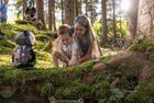 Mutter entdeckt gemeinsam mit ihrem Sohn und Maskottchen Elfi das kleine Elfendorf im Juppi Zauberwald in Reith i.A.  | © Tiroler Familiennester | shootandstyle 