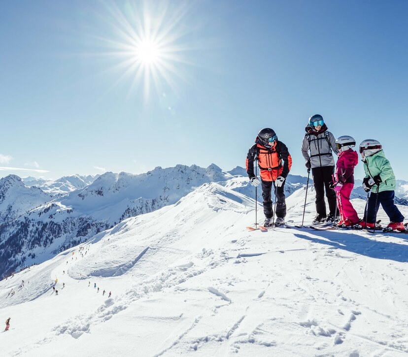 Eine Familie steht am Berg auf der Skipiste und freut sich schon auf die Pistenabfahrt im Ski Juwel Alpbachtal Wildschönau  | © Alpbachtal Tourismus | shootandstyle 