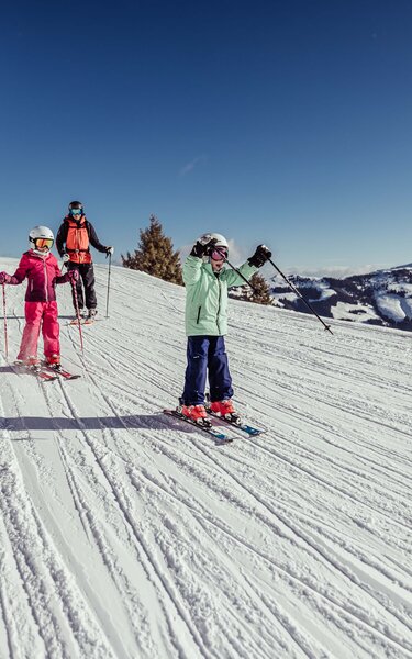 Eine Familie fährt gemeinsam der Skipiste in Alpbach entlang, die Kinder fahren vor, die Eltern hinten nach  | © Alpbachtal Tourismus | shootandstyle 