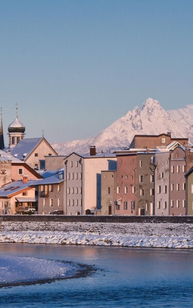 Zu sehen ist die kleine verschneite Stadt Rattenberg, mit ihren alten bunten Häusern, im Hintergrund ragen große verschneite Gipfel hervor  | © Alpbachtal Tourismus 